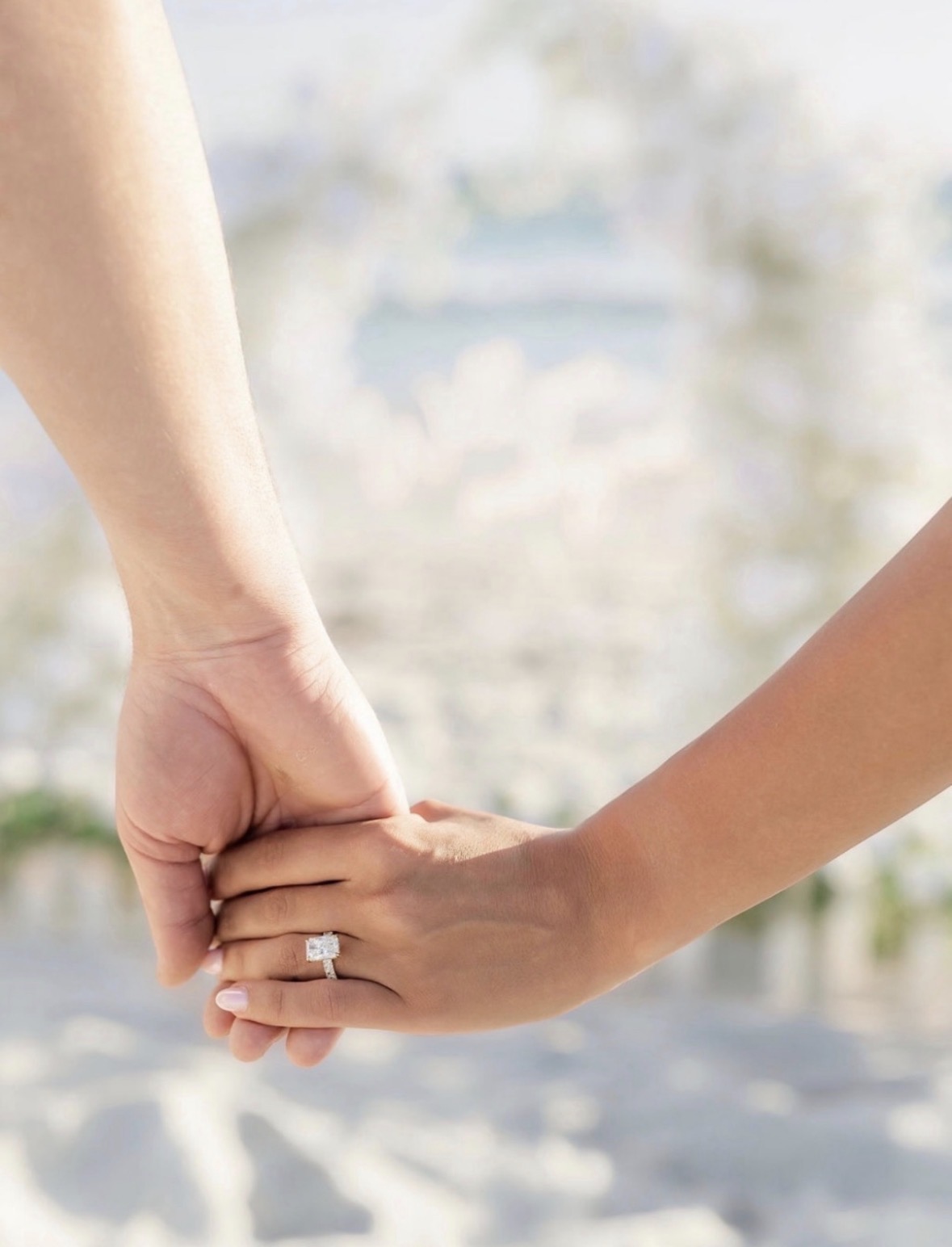 Radiant cut diamond engagement ring on hand, beach engagement